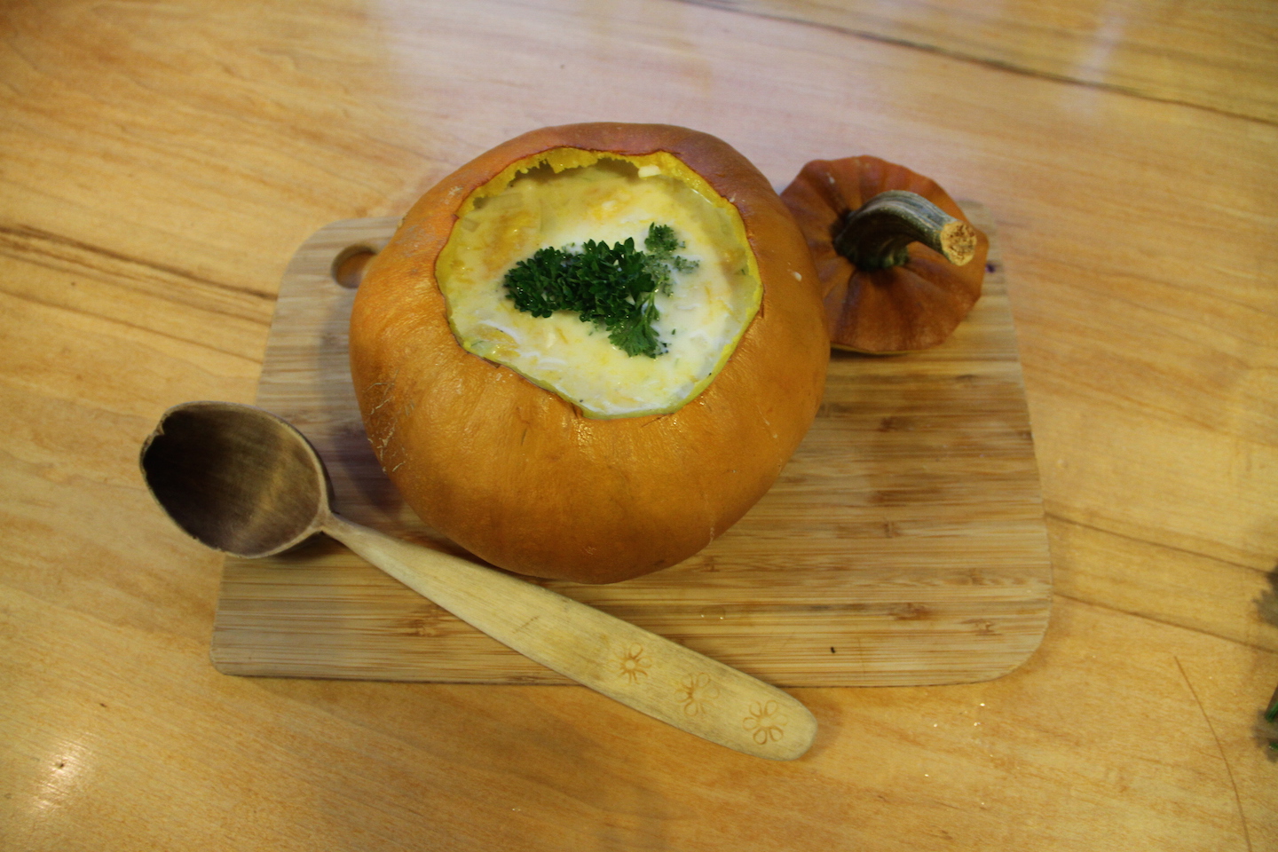 Homemade pumpkin soup served in it's own shell placed decoratively on a table.
