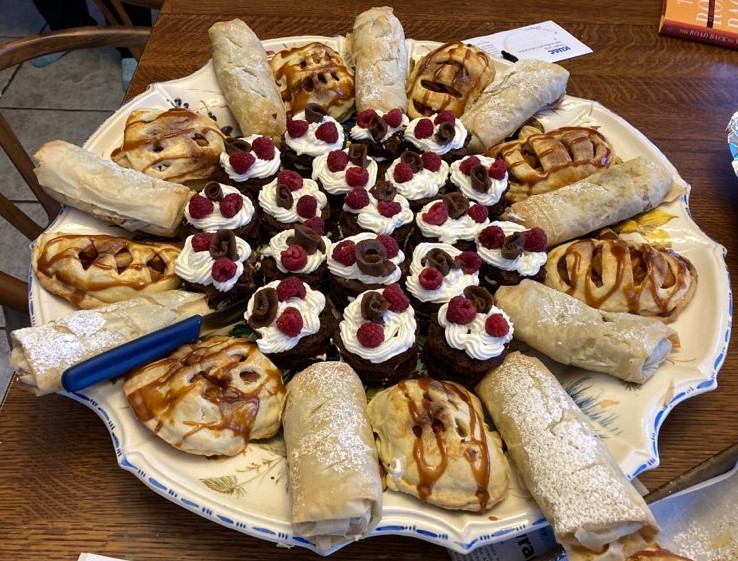 tray of deserts with raspberries on cupcakes