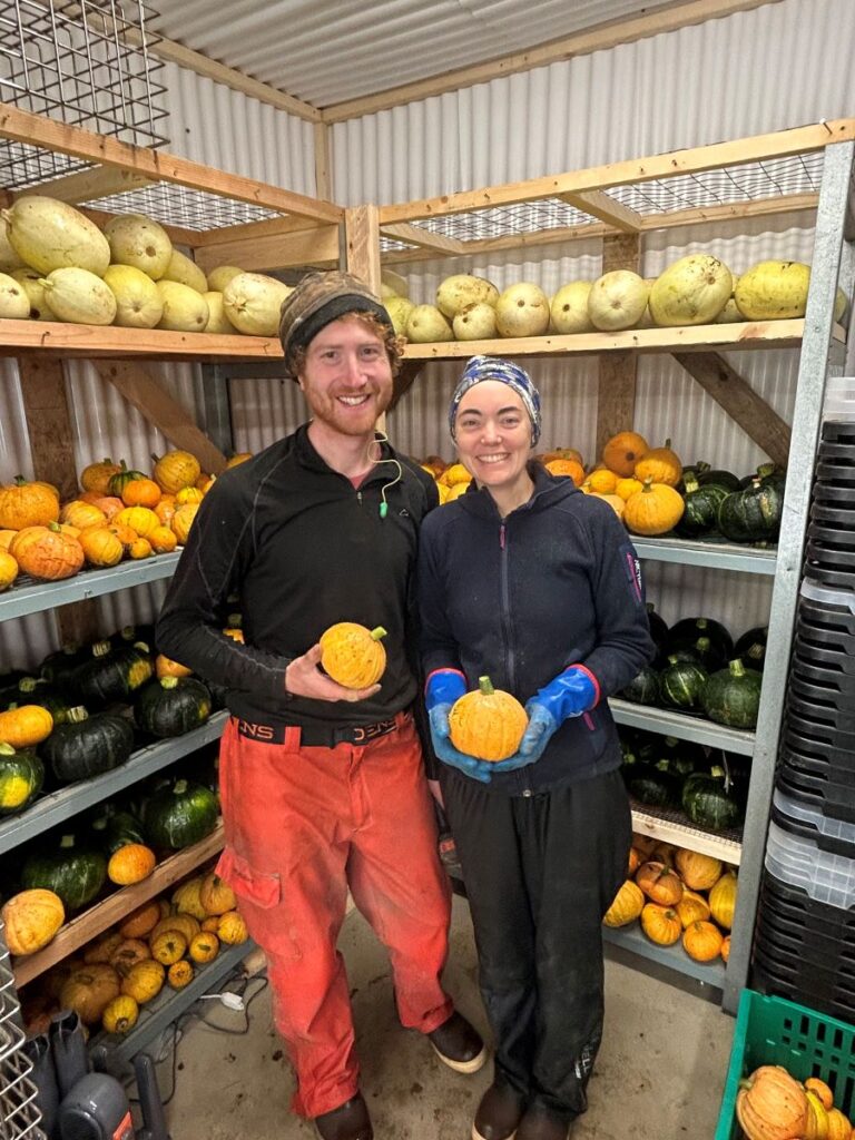 sam and danielle Knapp with winter squash on shelves behind them